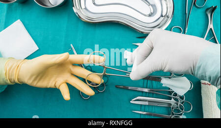 Chirurgien travaillant en salle d'opération, les mains avec des gants et de la suture des ciseaux holding, torundas image composicon conceptuel, horizontale Banque D'Images