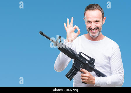 L'âge moyen des cadres supérieurs de l'homme criminel holding gun arme sur fond isolé ok faire signer avec les doigts, symbole excellent Banque D'Images