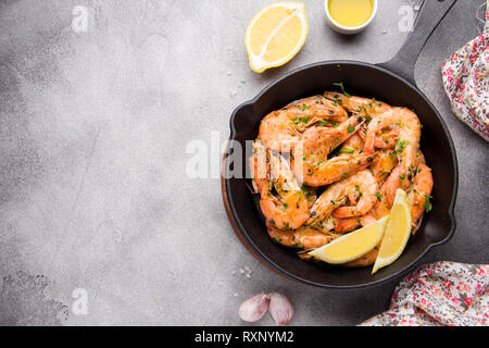 Crevettes frites en shell avec le persil, la coriandre, l'ail et l'huile dans la casserole. Savoureuse cuisine méditerranéenne, la nourriture végétarienne, protéines saines Banque D'Images