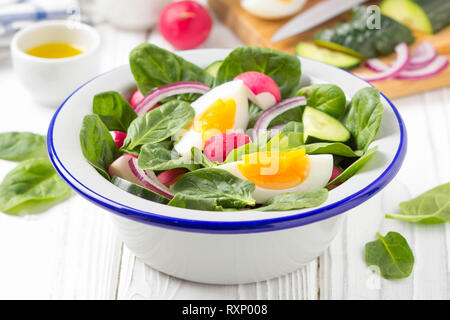 Salade d'épinards frais du printemps, le radis, le concombre et l'oeuf. Délicieux déjeuner, des aliments sains, de légumes d'été. Dans un bol blanc sur fond de bois Banque D'Images