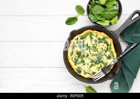 Omelette aux épinards et haricots, alimentation saine. L'oeuf et le lait Frittata, délicieux petit-déjeuner. En noir poêle à fond en bois blanc avec cop Banque D'Images