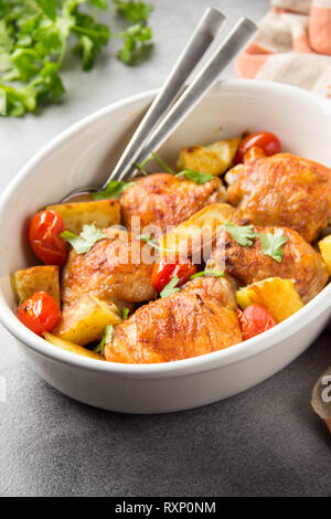 Cuisses de poulet au four (jambes) avec croûte croustillante, pommes de terre et les tomates cerises. Délicieux dîner fait maison simple, repas traditionnel. La cuisson de tous les jours Banque D'Images