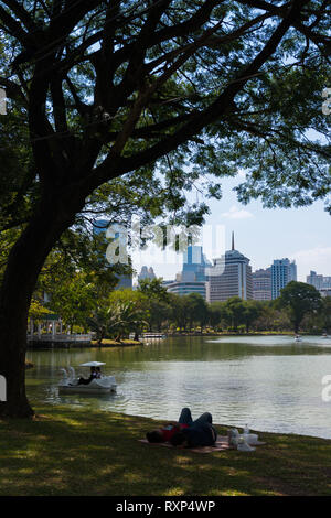 Se détendre sur l'herbe près du lac dans le parc Lumpini, Bangkok, Thaïlande Banque D'Images