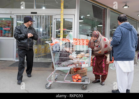 Une scène à l'extérieur de l'Apna Bazaar supermarché avec une famille & enfant dans un panier. Dans la région de Jackson Heights, Queens, New York City Banque D'Images