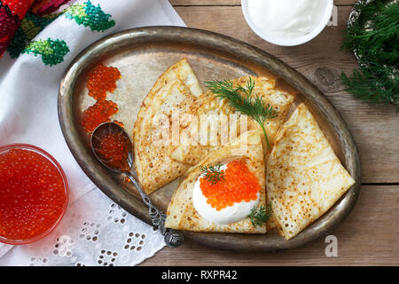 Crêpes maison avec du caviar rouge, de la crème fraîche et l'aneth servi avec de la vodka. De style rustique, selective focus. Banque D'Images