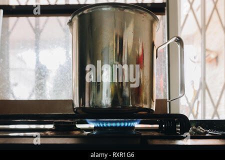 Lait électrique en acier inoxydable, tasse, pot sur une cuisinière. Cuisinière à gaz d'une flamme allumée, close-up Banque D'Images