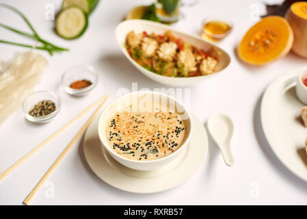 Vue rapprochée de délicieux dîner pour une sur nappe blanche. Dîner oriental, de la soupe avec des graines, tempura de crevettes et les nouilles avec les légumes de la préparation Banque D'Images