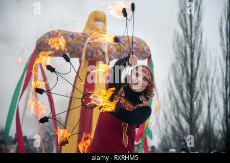 Tambov, Région de Tambov, en Russie. Mar 10, 2019. 10 mars 2019 dans le parc de la culture et des loisirs (Tambov, Russie) a tenu une maison de vacances de Maslenitsa. Pour les invités du festival a été préparé un concert, concours, spectacles, spectacle de feu. À la fin des vacances, la gravure traditionnelle de l'effigie de l'hiver (l'effigie de Maslenitsa) a eu lieu. C'est une ancienne tradition russe d'adieu à l'hiver et du printemps réunion. Dans les photo-une fille habillé comme un bouffon russe, avec des torches. Dans l'arrière-plan, un épouvantail de l'hiver Crédit : Demian Stringer/ZUMA/Alamy Fil Live News Banque D'Images