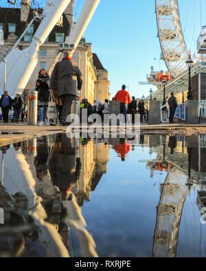 South Bank, Londres, Royaume-Uni. 10 Mar 2019. Les gens à pied en fin d'après-midi soleil sur London's South Bank. Après une journée de soleil et de la pluie, la fin de l'après-midi voit un retour du beau soleil du soir avec beaucoup de flaques et reflets près du London Eye. Credit : Imageplotter/Alamy Live News Banque D'Images