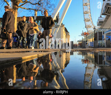 South Bank, Londres, Royaume-Uni. 10 Mar 2019. Les gens à pied en fin d'après-midi soleil sur London's South Bank. Après une journée de soleil et de la pluie, la fin de l'après-midi voit un retour du beau soleil du soir avec beaucoup de flaques et reflets près du London Eye. Credit : Imageplotter/Alamy Live News Banque D'Images