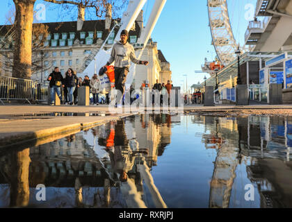 South Bank, Londres, Royaume-Uni. 10 Mar 2019. Les gens à pied en fin d'après-midi soleil sur London's South Bank. Après une journée de soleil et de la pluie, la fin de l'après-midi voit un retour du beau soleil du soir avec beaucoup de flaques et reflets près du London Eye. Credit : Imageplotter/Alamy Live News Banque D'Images