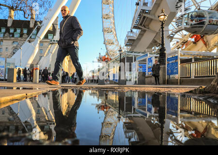 South Bank, Londres, Royaume-Uni. 10 Mar 2019. Les gens à pied en fin d'après-midi soleil sur London's South Bank. Après une journée de soleil et de la pluie, la fin de l'après-midi voit un retour du beau soleil du soir avec beaucoup de flaques et reflets près du London Eye. Credit : Imageplotter/Alamy Live News Banque D'Images