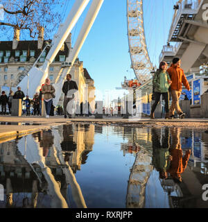 South Bank, Londres, Royaume-Uni. 10 Mar 2019. Les gens à pied en fin d'après-midi soleil sur London's South Bank. Après une journée de soleil et de la pluie, la fin de l'après-midi voit un retour du beau soleil du soir avec beaucoup de flaques et reflets près du London Eye. Credit : Imageplotter/Alamy Live News Banque D'Images