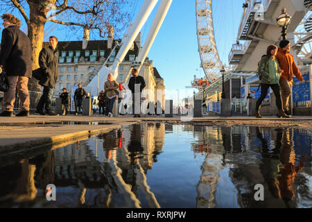 South Bank, Londres, Royaume-Uni. 10 Mar 2019. Les gens à pied en fin d'après-midi soleil sur London's South Bank. Après une journée de soleil et de la pluie, la fin de l'après-midi voit un retour du beau soleil du soir avec beaucoup de flaques et reflets près du London Eye. Credit : Imageplotter/Alamy Live News Banque D'Images