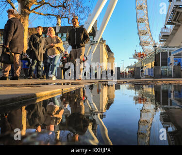 South Bank, Londres, Royaume-Uni. 10 Mar 2019. Les gens à pied en fin d'après-midi soleil sur London's South Bank. Après une journée de soleil et de la pluie, la fin de l'après-midi voit un retour du beau soleil du soir avec beaucoup de flaques et reflets près du London Eye. Credit : Imageplotter/Alamy Live News Banque D'Images