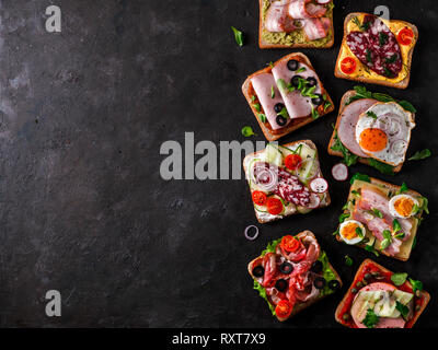 Ensemble de huit différents sandwiches avec de la viande, de l'espace pour copier du texte. Vue de dessus ou de télévision. Toasts viande assortiment sur fond noir. Idée créative, con Banque D'Images