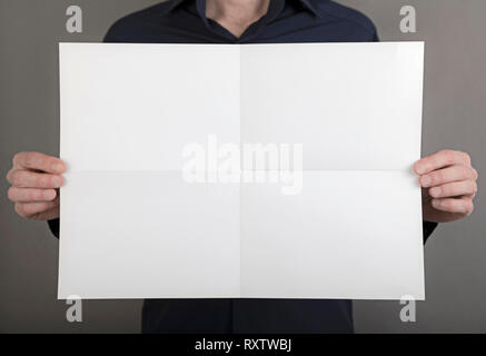 Un homme en chemise bleue holding a blank brochure Banque D'Images