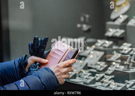 Femme prenant une photo avec un téléphone portable des alliances dans une bijouterie. La photo avec une faible profondeur. Banque D'Images