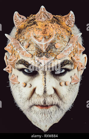 Tête avec des épines ou des verrues, visage couvert de paillettes, Close up. Démon sur visage sérieux, fond noir. Alien, démon, sorcier maquillage. Senior man Banque D'Images