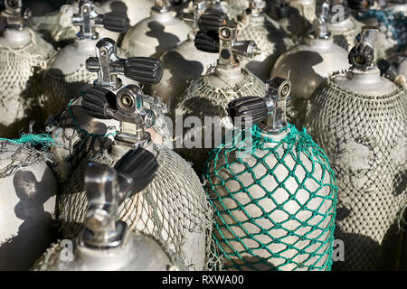 De nombreux réservoirs de plongée métallique recouverte de filets gris et vert stand à l'extérieur. Soleil brille sur eux. Libre photo horizontale. Banque D'Images