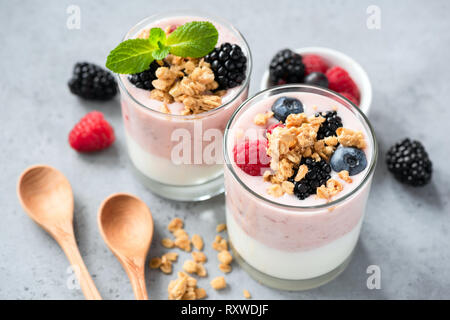 Berry fruits yogourt avec Granola et petits fruits rouges frais. Arrière-plan de béton. La saine alimentation, les régimes, la condition physique et sportive concept de vie Banque D'Images