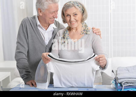 Portrait of happy senior couple pendant le repassage à la maison Banque D'Images