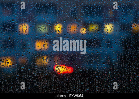 Gouttes de pluie sur la vitre à l'arrière-plan des fenêtres de formes multicolores Banque D'Images
