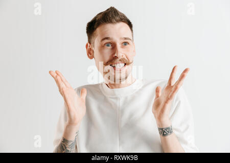 Wow. Attractive male avant mi-longueur sur portrait studio gris backgroud. Jeune homme barbu étonné émotionnel l'article avec la bouche ouverte. Les émotions humaines, l'expression faciale concept Banque D'Images