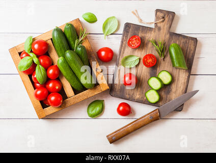 Les tomates biologiques et de concombre au basilic et le linge dans une serviette vintage boîte en bois sur la table en bois Banque D'Images