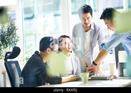 Groupe de quatre professionnels de jeunes dirigeants d'Asie qui travaillent ensemble en discutant affaires réunion bureau en bureau. Banque D'Images