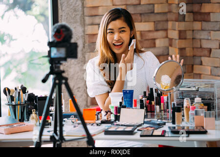 Charmante fille asiatique recording vlog. Beauty blogger présentant un miroir devant la caméra de cosmétiques Banque D'Images