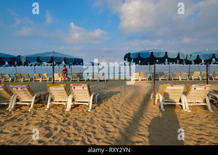 Sur un matin tôt, Karon Beach à Phuket, Thaïlande, ouvert avec des chaises et des parasols alignés, est presque vide, sauf pour une femme seule dans l'b/g Banque D'Images