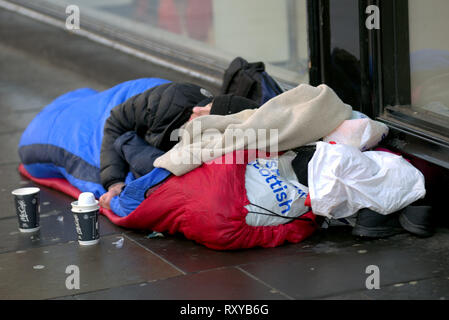 Les jeunes sans-abri Glasgow garçon dort sur la masse dans la porte sur rue en couette avec sac écossais comme oreiller et mccafe cups comme company Banque D'Images