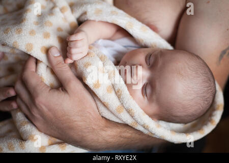 Jeune père tenant sa douce adorable slepping enfant nouveau-né. Tourné à l'intérieur, de concept de droit Banque D'Images