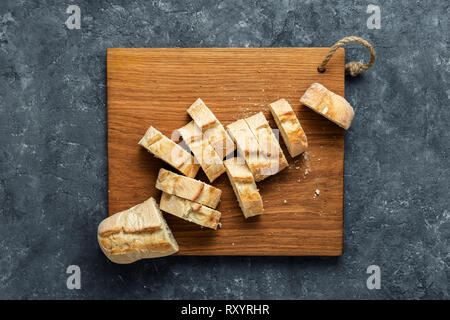 Tranches de baguette fraîche sur la frontière en bois sombre sur fond de pierre Vue de dessus Banque D'Images