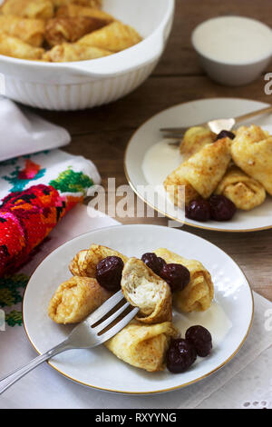 Crêpes maison farcies au fromage blanc et aux raisins secs, servi avec crème sure et cerise. Moldave traditionnelle roumaine ou dessert, fo sélective Banque D'Images