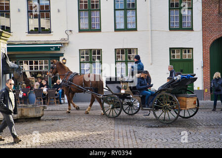 BRUGES, BELGIQUE - 17 février 2019 : place avec les touristes, les chevaux avec chariots, des bâtiments historiques Banque D'Images
