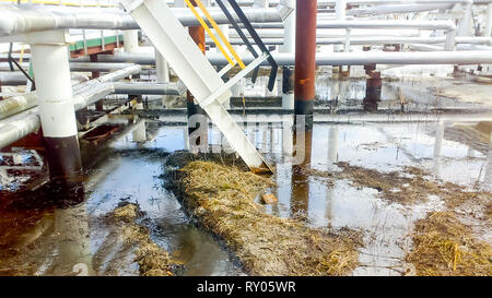 L'huile renversée sur un sol sablonneux à proximité de pipelines et de production. Les fuites d'huile pendant le fonctionnement et la réparation Banque D'Images