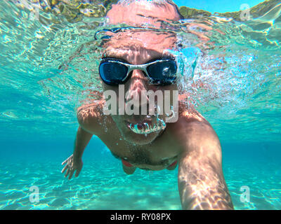 Vue sous-marine d'un plongeur jeune homme nager dans la mer. Des bulles d'air sortant de la bouche et le nez Banque D'Images