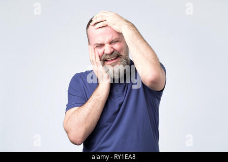 L'homme mature avec barbe est en train de pleurer dans la panique. Banque D'Images