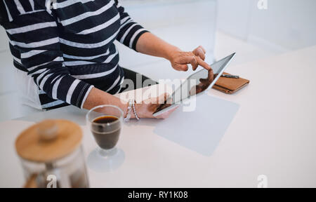 Close up image of a young woman, en utilisant sa tablette à la maison , dans la cuisine. Avec café et ordinateur portable sur la table Banque D'Images