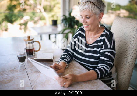 Portrait of a young woman smiling, en utilisant sa tablette à la maison , à l'extérieur sur le balcon. Belle femme âgée et défilement Banque D'Images