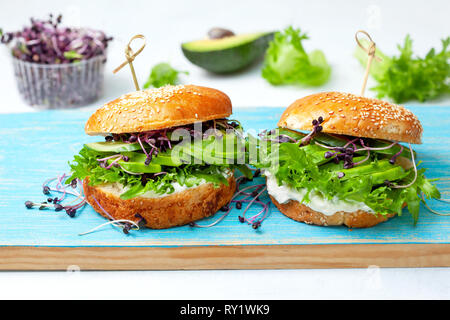 Burger vert avec de l'avocat, le concombre, le fromage à la crème et pousses sur un panneau bleu Banque D'Images