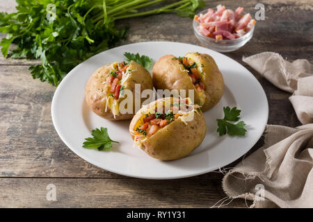 Pommes de terre farcies au jambon et fromage sur la plaque sur une table en bois Banque D'Images