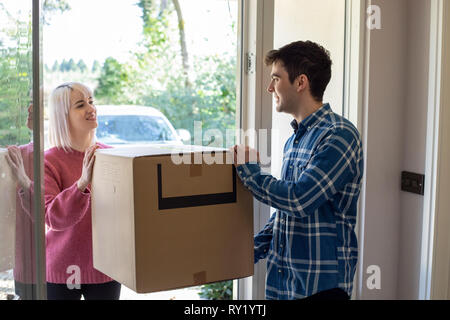 Jeune couple Carrying Cases dans nouvelle maison le jour du déménagement Banque D'Images