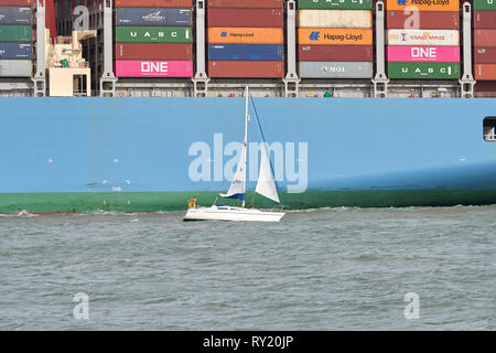 Le petit bateau à voile, DRIFTER, passe à proximité de la porte-conteneurs géant, MOL, hommage à son entrée dans le Port de Southampton après un voyage de 26 jours. Banque D'Images