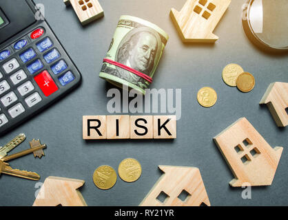 Maisons en bois, d'une calculatrice, clefs, monnaie et les blocs avec le mot risque. Les risques d'investir dans l'immobilier. Le concept de risque hypothécaire. La perte de p Banque D'Images
