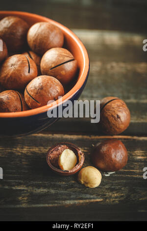 Macadamia bio dans Bol en céramique sur table en bois. Un espace réservé au texte Banque D'Images