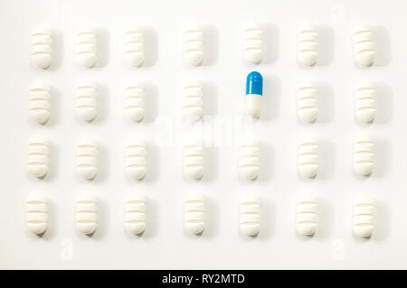 Beaucoup de pilules blanches un bleu sur fond blanc Banque D'Images