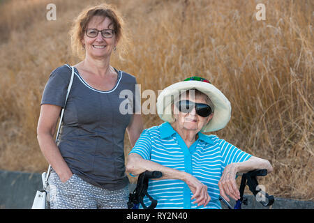 Senior woman sitting on mobile walker avec sa fille adulte-Victoria, Colombie-Britannique, Canada. Banque D'Images